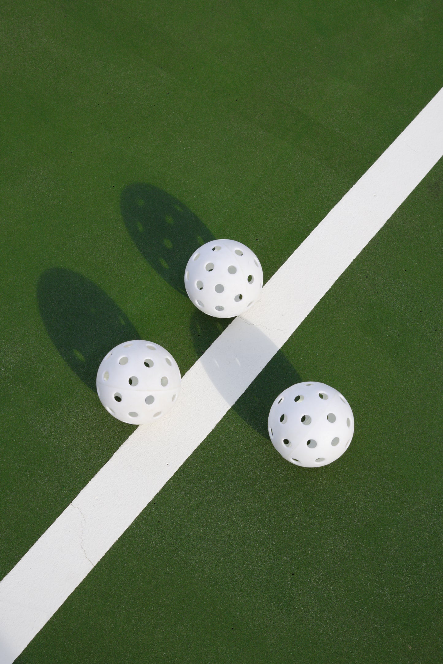 white pickleballs on green court